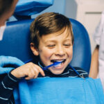 Ein Kind beim Zahnarzt demonstriert, wei man sich die Zähne putzt
