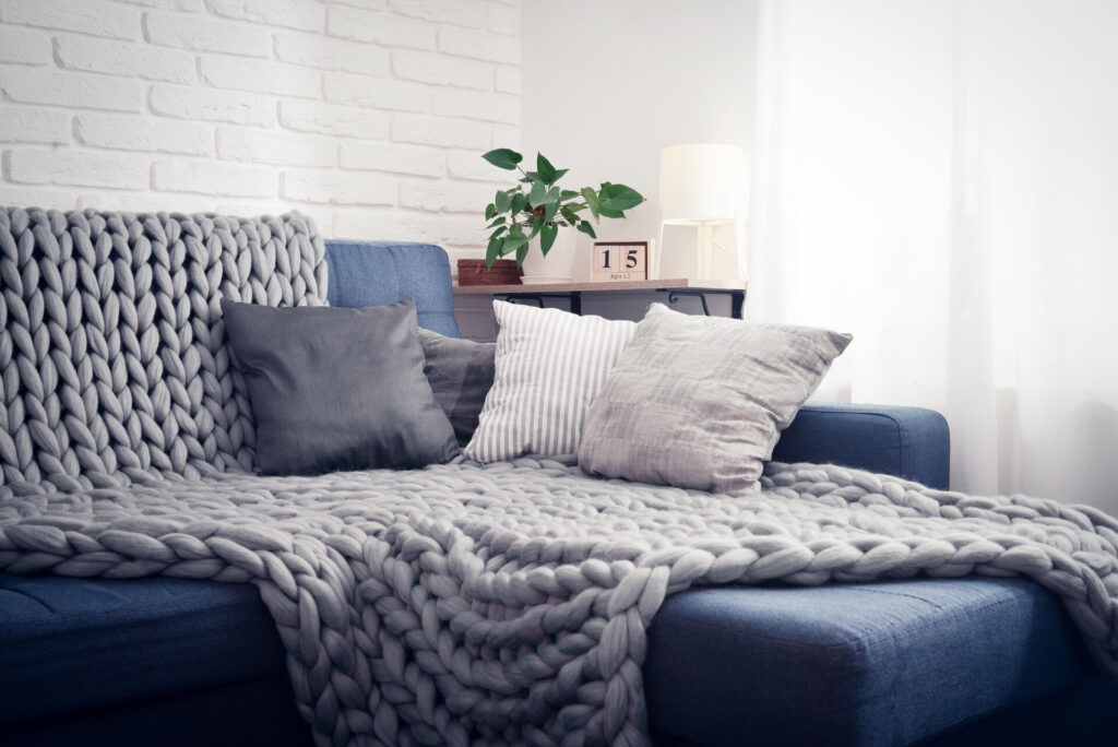 Graue Alpaka Decke auf Couch mit Kissen im Innenraum eines Wohnzimmers