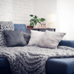 Graue Alpaka Decke auf Couch mit Kissen im Innenraum eines Wohnzimmers