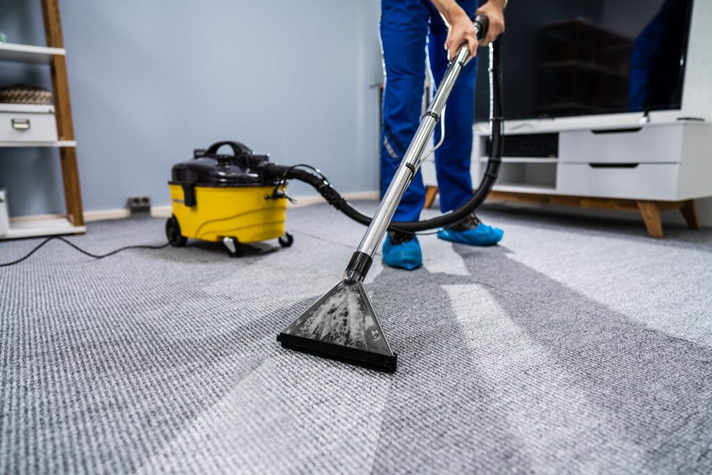 Mann saugt Teppich mit speziellem Staubsauger