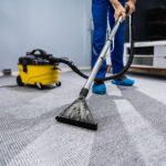Mann saugt Teppich mit speziellem Staubsauger