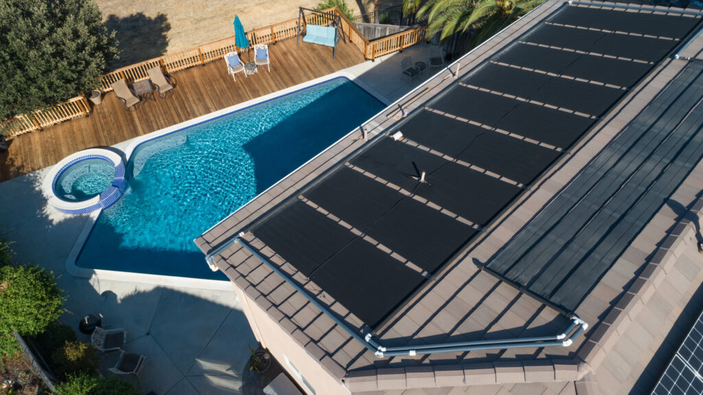 Thermische Sonnenkollektoren, die auf dem Dach eines großen Hauses installiert und mit dem Pool verbunden sind