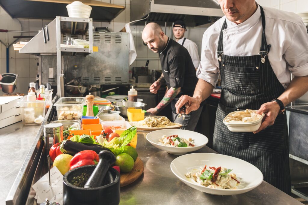 Köche bereiten Speisen in professioneller Restaurantküche zu | Kühlvitrine
